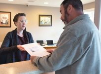Receptionist Hands Dental Care Patient Paperwork at Our Newport Oregon Dentist Office